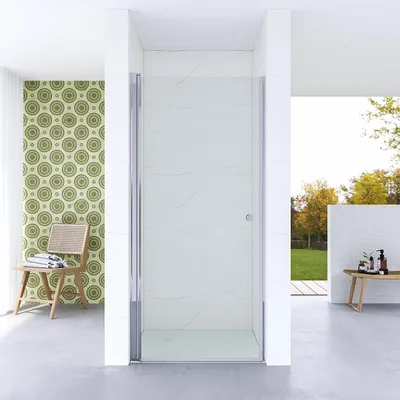 A modern bathroom with a glass shower enclosure, patterned wallpaper, and a chair with towels.