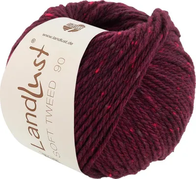 A ball of burgundy tweed yarn with red and gray flecks, with a label wrapped around it.