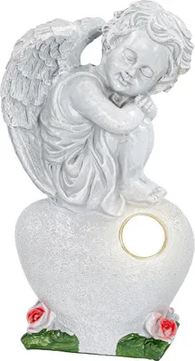 A white angel statue sitting on a heart, with roses at the base.