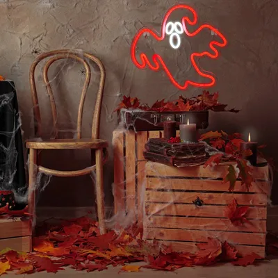 A Halloween-themed scene with a ghost neon sign, wooden crates, fallen leaves, and cobwebs.