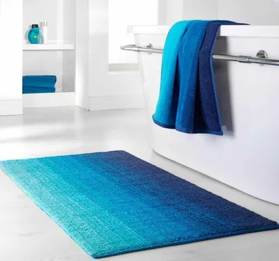 A bathroom scene with a rug and towels.