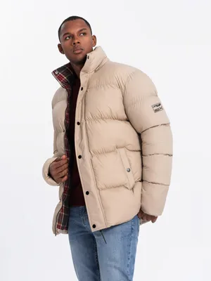 A man wearing a beige puffer jacket with a plaid lining.