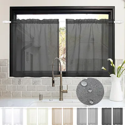 A kitchen sink area with dark gray sheer curtains hanging in the window above it.