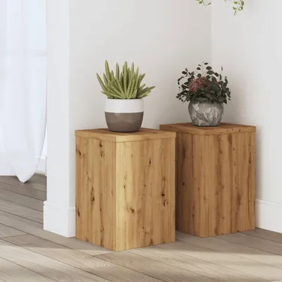 Two wooden cube-shaped plant stands are placed in a corner of a room, each holding a potted plant. The stands have a natural wood grain texture.