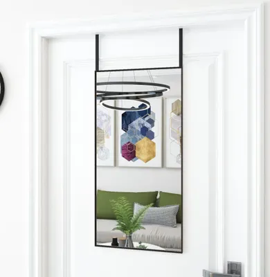 A mirror hanging on a door, reflecting a room with artwork and furniture.