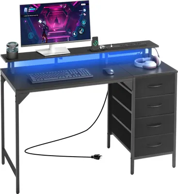 A black computer desk with a monitor, keyboard, mouse, headphones, and LED lighting.