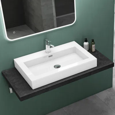 A modern bathroom sink with a faucet, mounted on a dark countertop against a green wall.