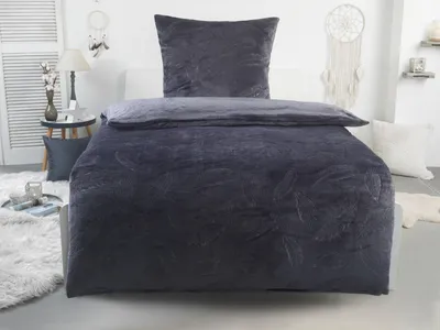 A bed with dark gray bedding, including a duvet and pillow, in a bedroom setting.