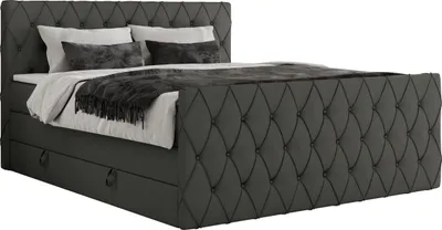A studio shot of a gray upholstered boxspring bed with a mattress and pillows.