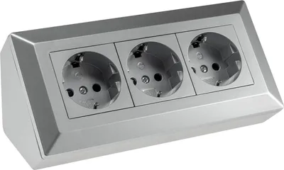 A silver-colored power strip with three electrical outlets, shown from a slightly elevated front-side angle against a white background.