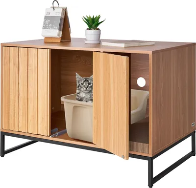 A cat is inside a wooden cabinet designed to hide a litter box. The cabinet has a door that is partially open, revealing the cat and the litter box. There are also decorative items on top of the cabinet.
