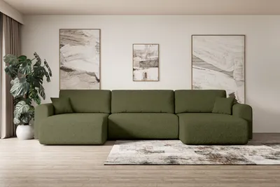 A modern living room with a large green sectional sofa, abstract art on the wall, and a large potted plant.