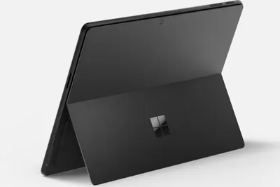 A black Microsoft Surface Pro tablet is shown from a rear-facing, slightly angled perspective, standing on its kickstand against a light gray background.