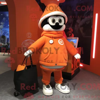 Produktbild von Maskottchen-Charakter REDBROKOLY eines orangefarbenen Zirkusdirektors mit Pullover und Tragetaschen