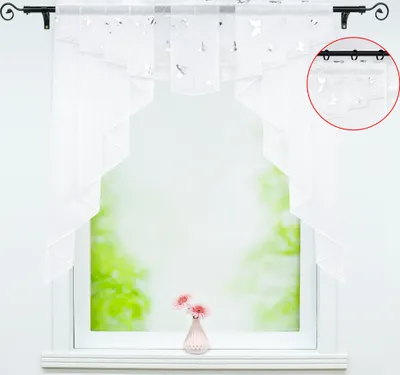 A white sheer curtain with butterfly pattern hanging on a window rod.
