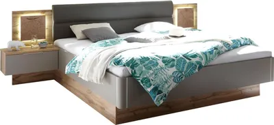 A modern bed with a headboard and two nightstands, set against a white background.