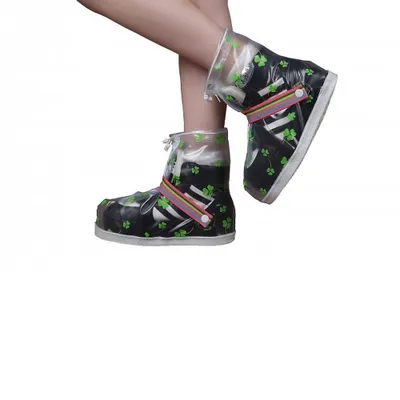 A person's legs wearing rain boot covers with a clover pattern.