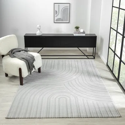 A modern living room with a rug, chair, and console table.