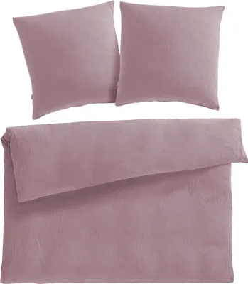 A mauve-colored duvet cover and two pillowcases are neatly folded and arranged on a white background.