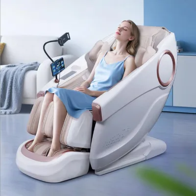 A woman is relaxing in a white and beige massage chair, with a phone holder and screen attached.