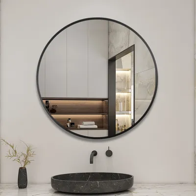 A round mirror with a black frame is mounted on a wall above a sink.