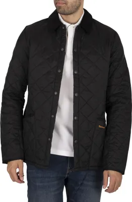 A man wearing a black quilted jacket over a white polo shirt and blue jeans.