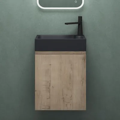 A modern bathroom vanity with a black sink and a wood-grain cabinet, set against a textured green wall.