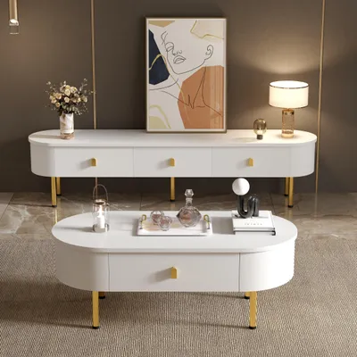 A living room scene featuring a white TV stand and coffee table set with gold accents, a painting on the wall, and a lamp.
