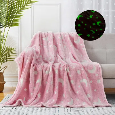 A pink blanket with glow-in-the-dark stars and moons is draped over a sofa in a living room setting.