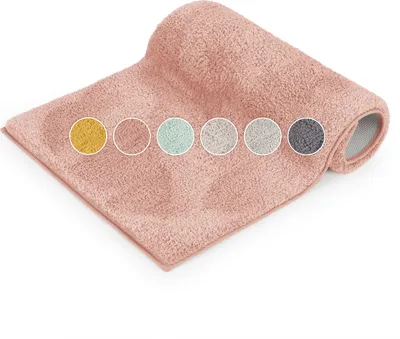 A rolled-up pink bath mat is shown on a white background with several color swatches displayed in circles on top of it.