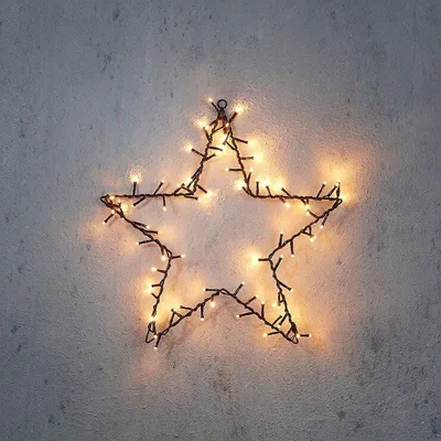A star-shaped string of lights is mounted on a textured wall.
