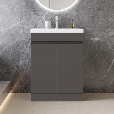 A modern bathroom vanity with a sink and cabinet against a marble-tiled wall.