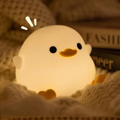 A cute, glowing duck-shaped night light is nestled in a soft, textured blanket.