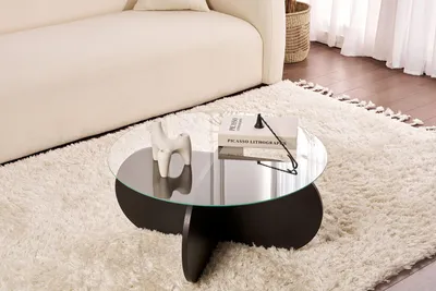 A coffee table with a decorative item and books on it, placed on a rug next to a sofa.