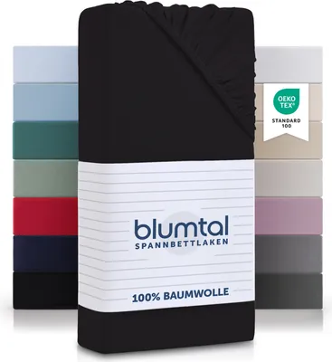 A stack of folded fitted sheets in various colors, with a black sheet prominently displayed in the foreground.