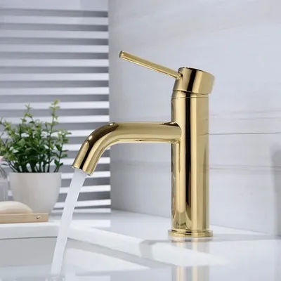 A close-up shot of a gold faucet with water running into a sink.