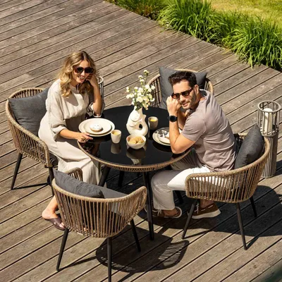 A couple enjoys a meal at a patio table on a wooden deck.