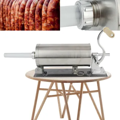 A stainless steel sausage stuffer sits on a wooden table.