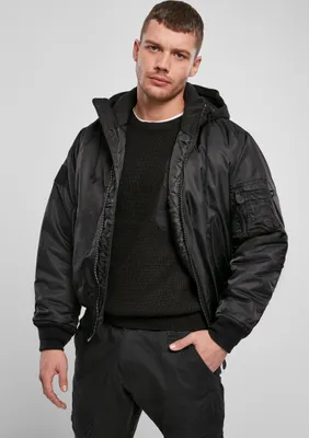 A man wearing a black bomber jacket and black sweater.