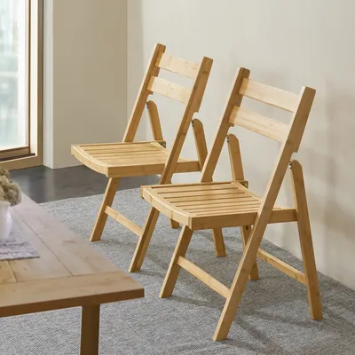 Two wooden folding chairs are shown in a room with a wooden table in the foreground.