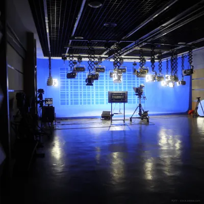 A television studio with a blue screen and lighting equipment.