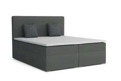 A dark gray boxspring bed with two pillows on a white background.