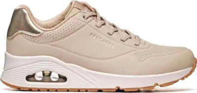 A side view of a beige Skechers sneaker with gold accents.