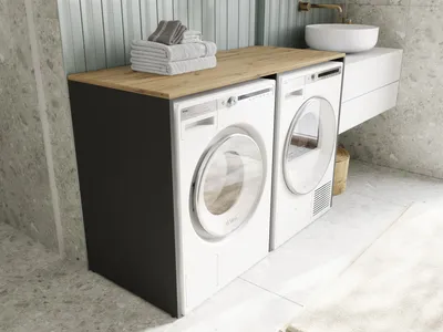 A laundry room with a washing machine and dryer under a wooden countertop.