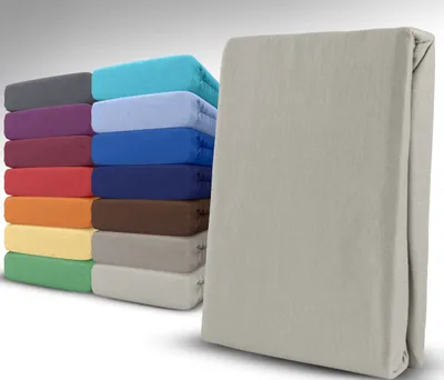 A stack of folded fitted sheets in various colors, with one gray fitted sheet in the foreground.