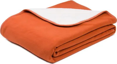 A folded blanket with an orange exterior and a white interior.