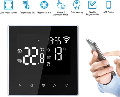 A digital thermostat is shown on a white background, with a hand holding a smartphone next to it, suggesting app control.