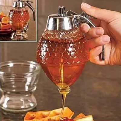 A hand is holding a honey dispenser, pouring honey onto waffles.