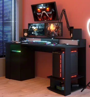 A gaming desk setup with multiple monitors, a computer tower, speakers, and LED lighting.