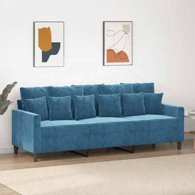 A blue velvet sofa with multiple cushions is shown in a room with two abstract paintings on the wall.